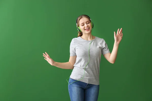 Krásná mladá žena poslouchá hudbu a tanec na barevném pozadí — Stock fotografie