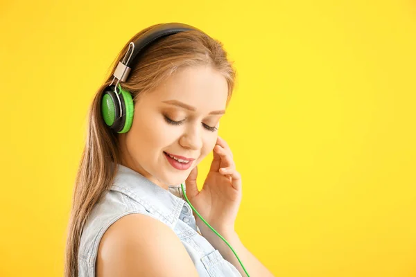 Beautiful young woman listening to music against color background — Stock Photo, Image