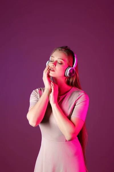Beautiful young woman listening to music against color background — Stock Photo, Image