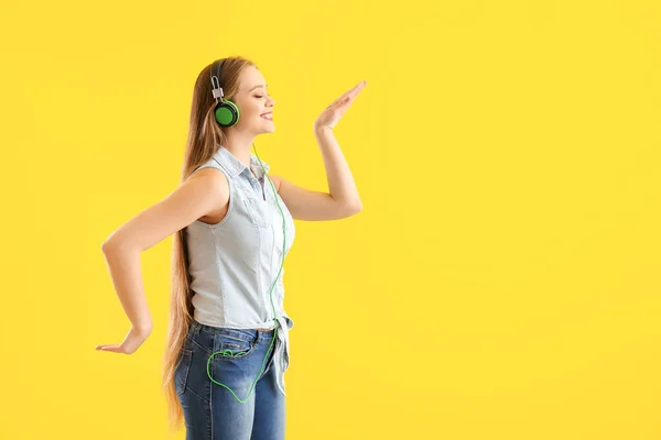 Bella giovane donna che ascolta musica e danza sullo sfondo di colore — Foto Stock