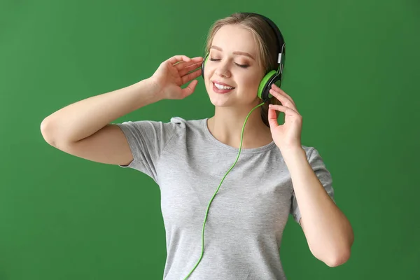 Beautiful young woman listening to music against color background — Stock Photo, Image