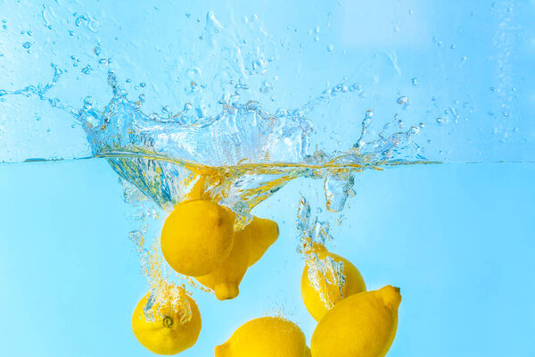 Falling of lemons into water on light background