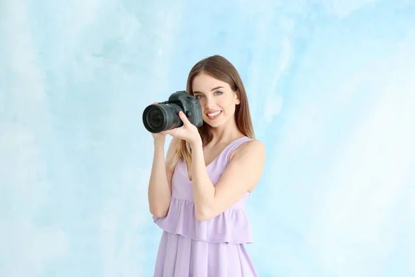 Young female photographer on color background — Stock Photo, Image