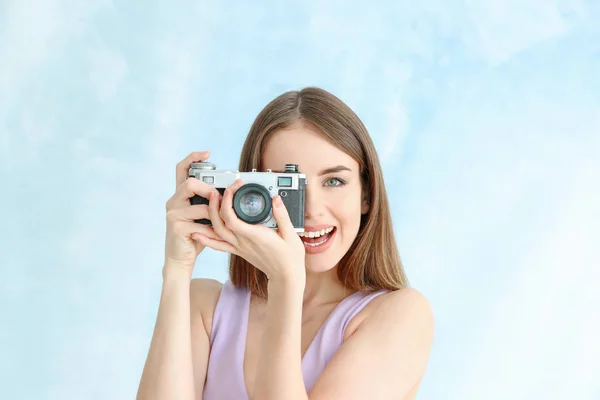 Young female photographer on color background — Stock Photo, Image