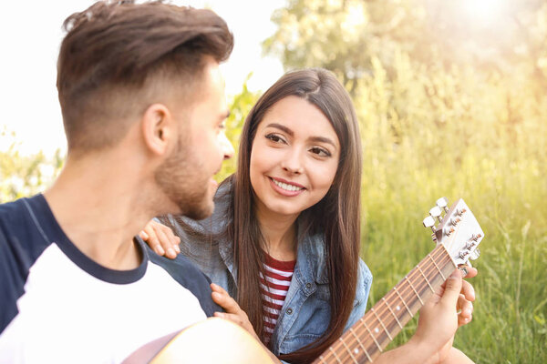 Young couple with guitar on picnic in park