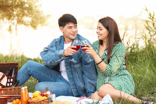 Νεαρό ζευγάρι πίνοντας κρασί για πικ-νικ στο πάρκο — Φωτογραφία Αρχείου