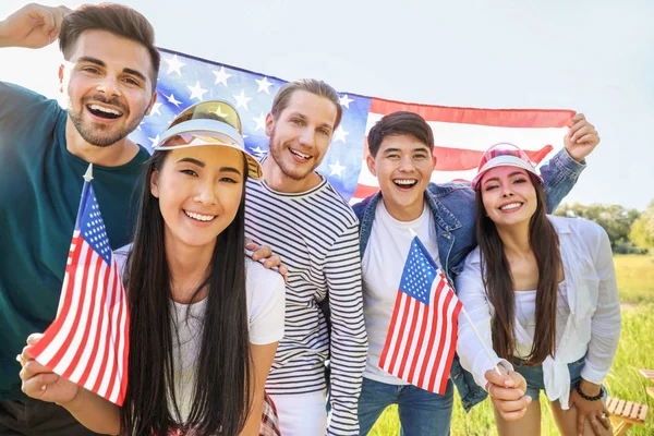 Young people with USA flags outdoors. Independence Day celebration