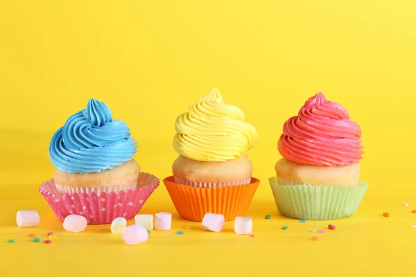 Doces cupcakes saborosos no fundo da cor — Fotografia de Stock