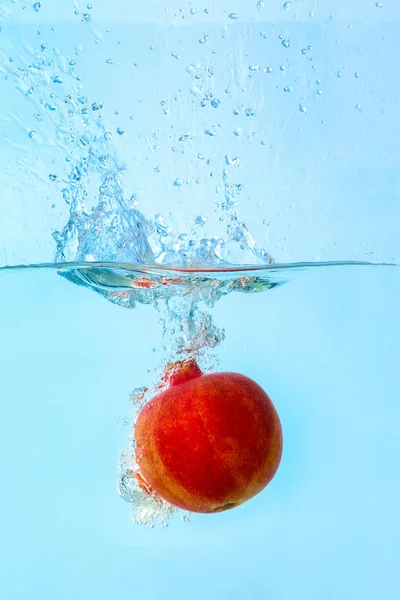 Falling of pomegranate into water on light background Stock Photo