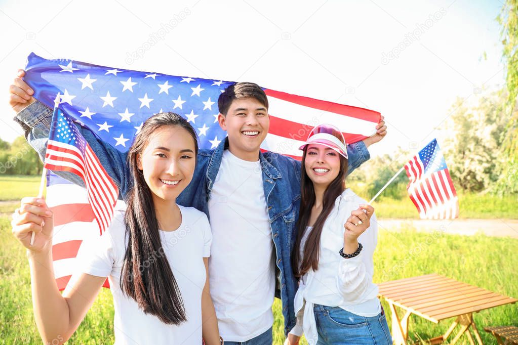 Young people with USA flags outdoors. Independence Day celebration