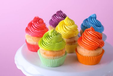 Renk arka planda tatlı lezzetli cupcakes ile stand