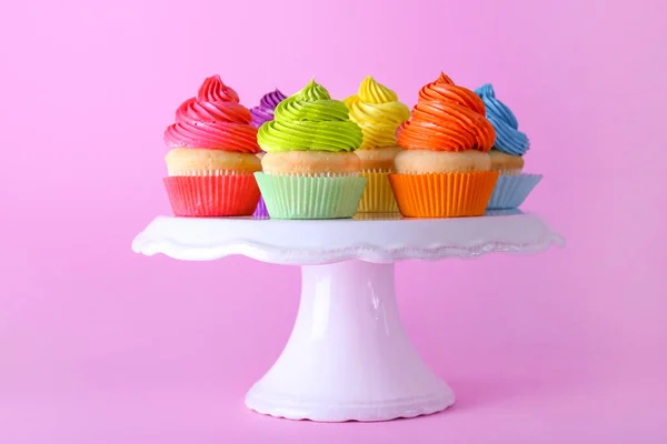 Stand with sweet tasty cupcakes on color background — Stock Photo, Image