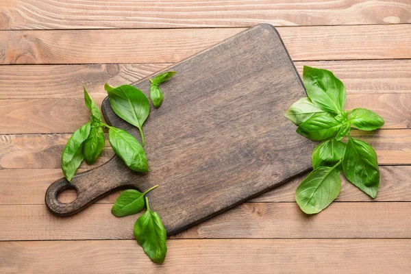 Wooden board with fresh basil on table — Stock Photo, Image