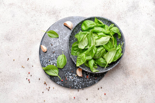 Plate with fresh basil and spices on light background