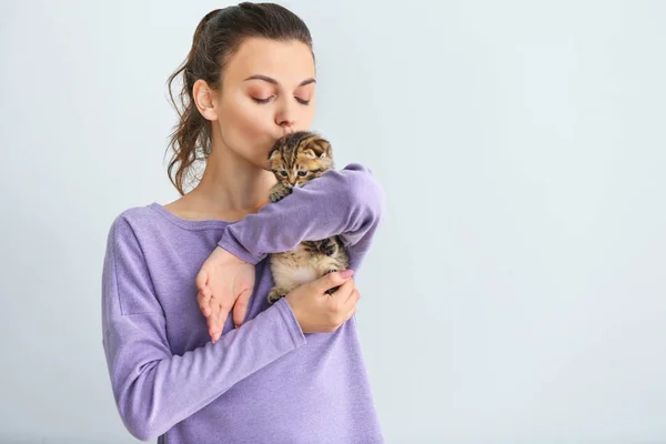 Beautiful young woman with cute little kitten on light background — Stock Photo, Image