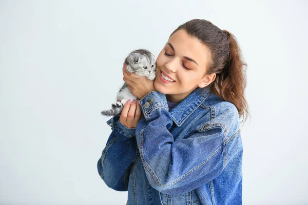 Beautiful young woman with cute little kitten on light background — Stock Photo, Image