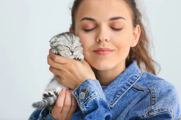 Hermosa mujer joven con lindo gatito en fondo claro — Foto de Stock