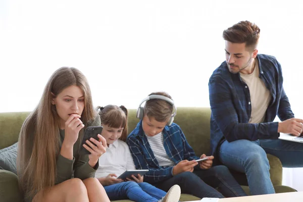 Família viciada em tecnologias modernas com dispositivos sentados no sofá em casa — Fotografia de Stock