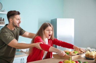 Genç adam mutfakta bağımlısı kadından gıda ile tepsi almaya çalışıyor