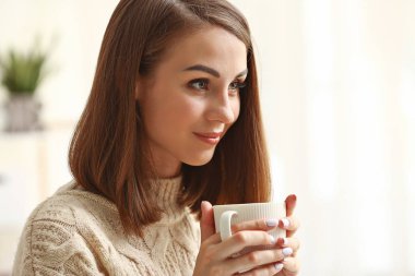 Güzel genç bayan evde çay içiyor.