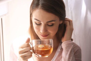 Güzel genç bayan evde çay içiyor.