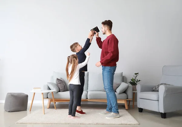 Hysteric children with addiction to modern technologies trying to take tablet computer from father at home — Stock Photo, Image