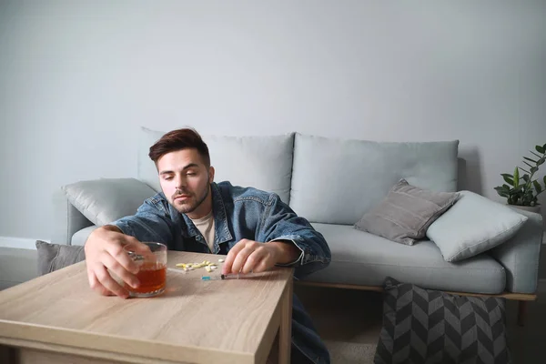 Young man with addiction to alcohol and drugs at home — Stock Photo, Image