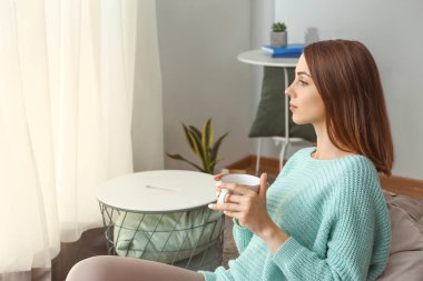 Güzel genç bayan evde çay içiyor.