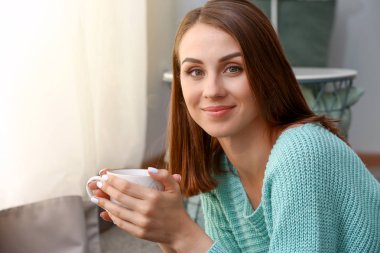 Güzel genç bayan evde çay içiyor.