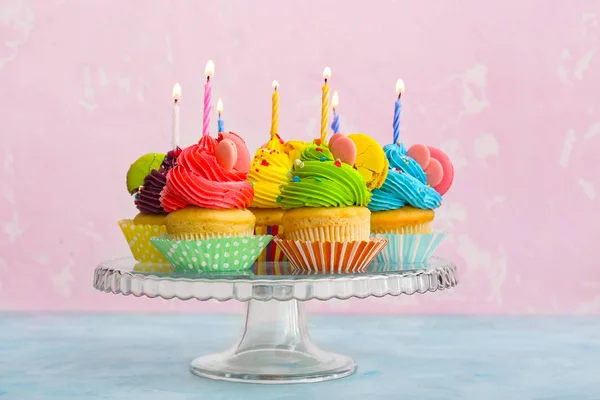 Doces cupcakes saborosos em pé contra fundo de cor — Fotografia de Stock