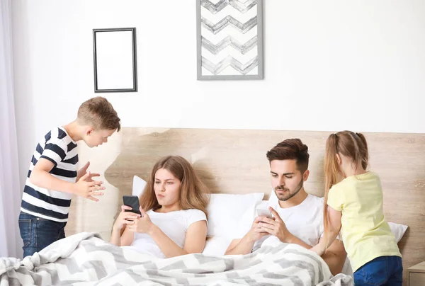 Kinderen scolding ouder met verslaving aan moderne technologieën in de slaapkamer — Stockfoto