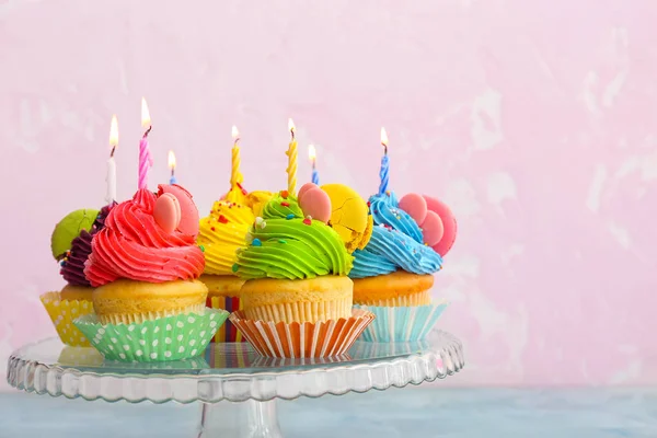 Doces cupcakes saborosos em pé contra fundo de cor — Fotografia de Stock