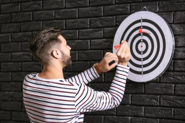 Koyu tuğla duvarda dart tahtası yakınında adam