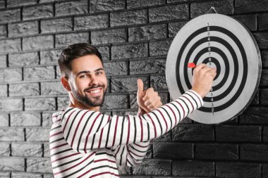 Koyu tuğla duvarda dart tahtası yakınında adam