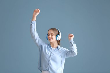 Müzik dinleyen ve arka planda dans eden güzel genç bir kadın.