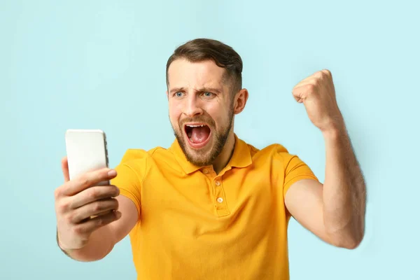 Feliz homem de sucesso com telefone celular em fundo de cor — Fotografia de Stock