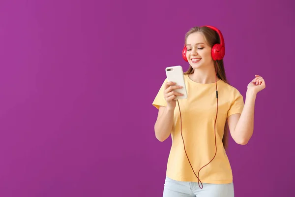 Красивая молодая женщина слушает музыку на цветном фоне — стоковое фото