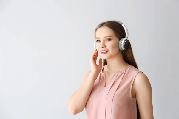 Beautiful young woman listening to music on light background — Stock Photo, Image