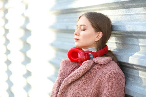 Mooie jonge vrouw met hoofdtelefoon buitenshuis — Stockfoto