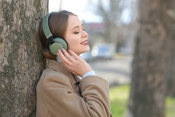 Όμορφη νεαρή γυναίκα να ακούτε μουσική στο πάρκο — Φωτογραφία Αρχείου