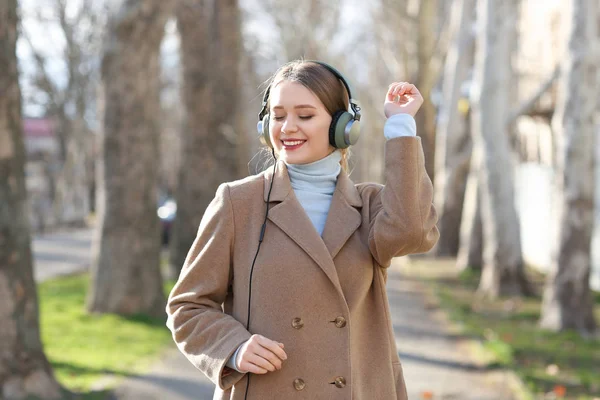 Mooie jonge vrouw, luisteren naar muziek in park — Stockfoto