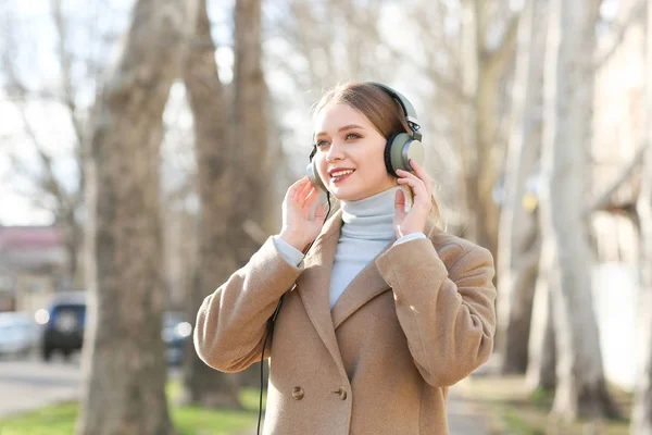 Mooie jonge vrouw, luisteren naar muziek in park — Stockfoto