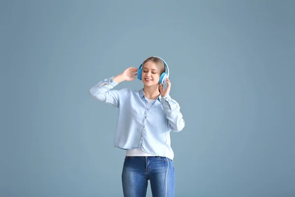 Mooie jonge vrouw luisteren naar muziek en dansen tegen kleur achtergrond — Stockfoto