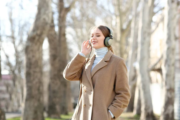 Mooie jonge vrouw, luisteren naar muziek in park — Stockfoto