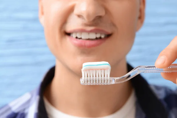Handsome man with toothbrush and paste on color background, closeup — Stock Photo, Image