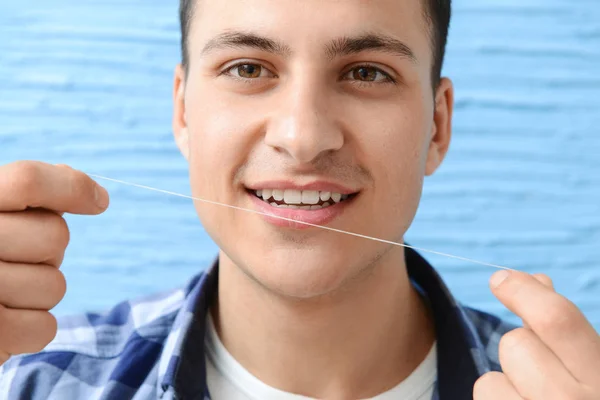 Knappe man met tandheelkundige floss op kleur achtergrond — Stockfoto