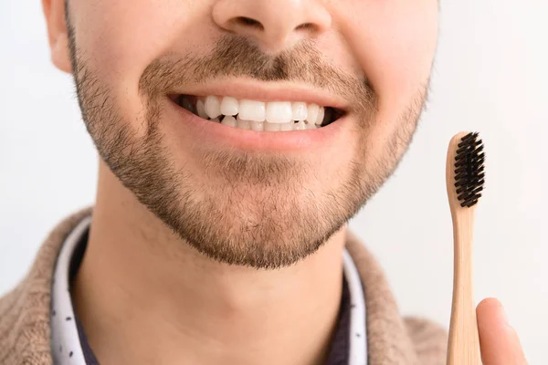 Knappe man met tandenborstel op lichte achtergrond, close-up — Stockfoto