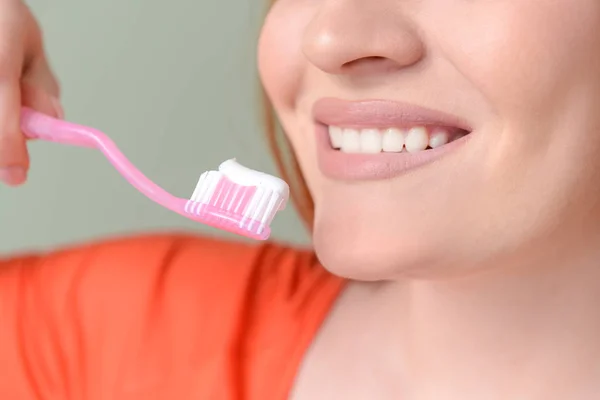 Mulher bonita com escova de dentes e colar em fundo de cor, close-up — Fotografia de Stock