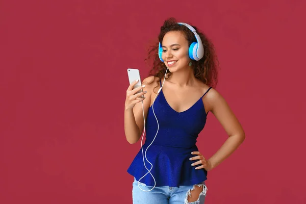 Hermosa mujer joven escuchando la música en el fondo de color — Foto de Stock