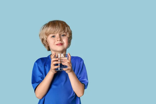 Lindo niño pequeño con vaso de agua dulce en el fondo de color — Foto de Stock